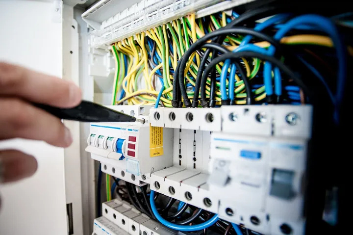 Destornillador apretando una borna en un cuadro eléctrico, con los magnetotérmicos y diferenciales montados y el cableado peinado por encima