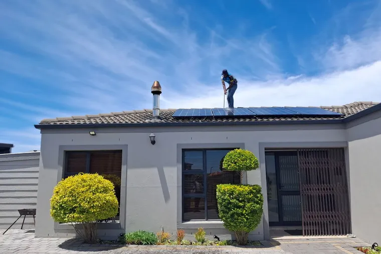 Operario trabajando sobre la cubierta de una vivienda unifamiliar durante el montaje de una instalación de placas solares