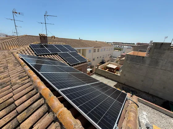 Dos filas de paneles solares montadas sobre el tejado de teja de una vivienda entre medianeras