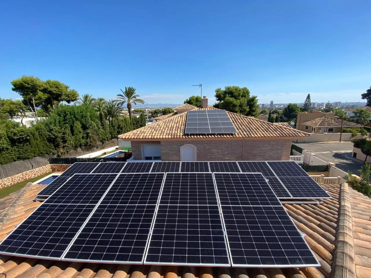 Instalación fotovoltaica de MSG sobre una terraza urbana, con el campanario de la iglesia y las calles del municipio alrededor