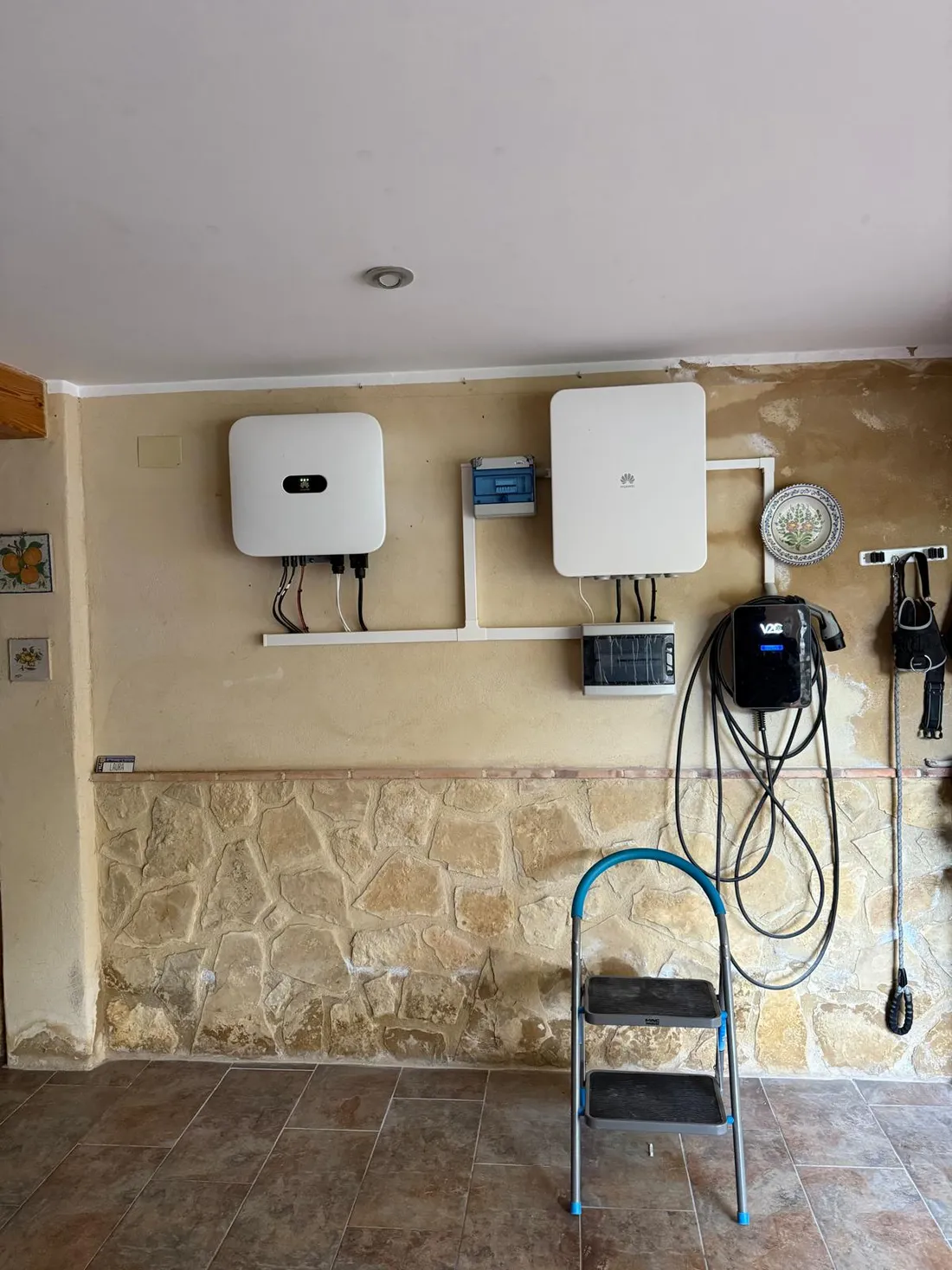 Inversor Huawei, batería y cuadro de protecciones alineados en la pared del garaje, junto al cargador para vehículo eléctrico