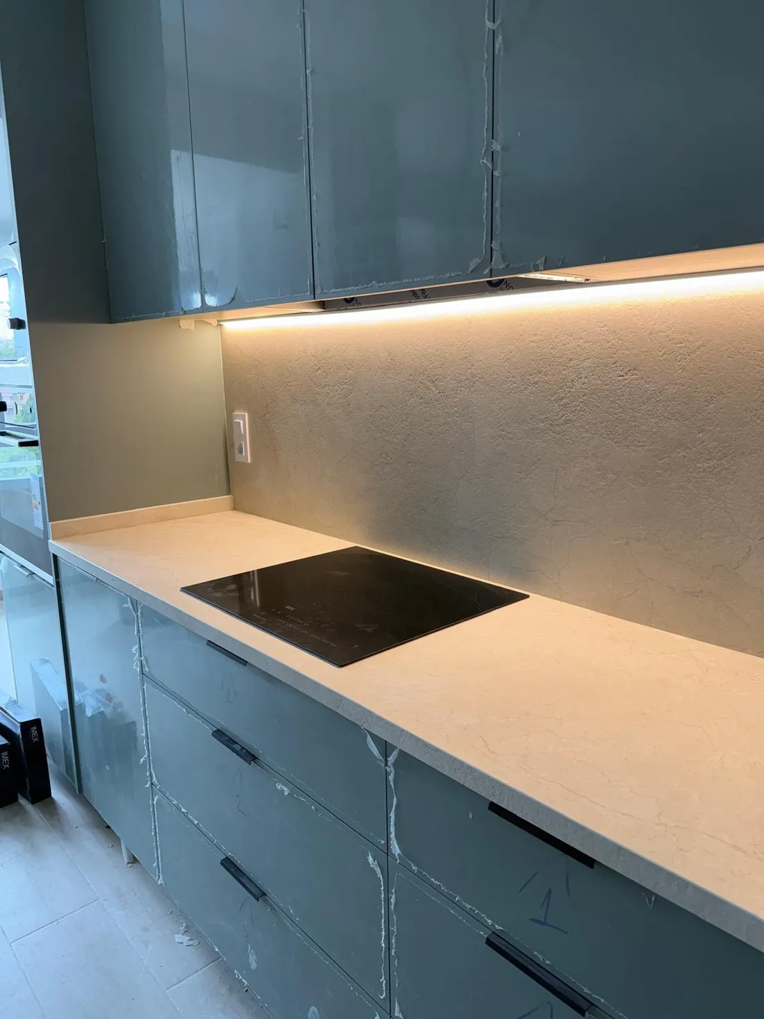 La misma cocina en escorzo, con la línea de luz recorriendo todo el mueble alto hasta la ventana