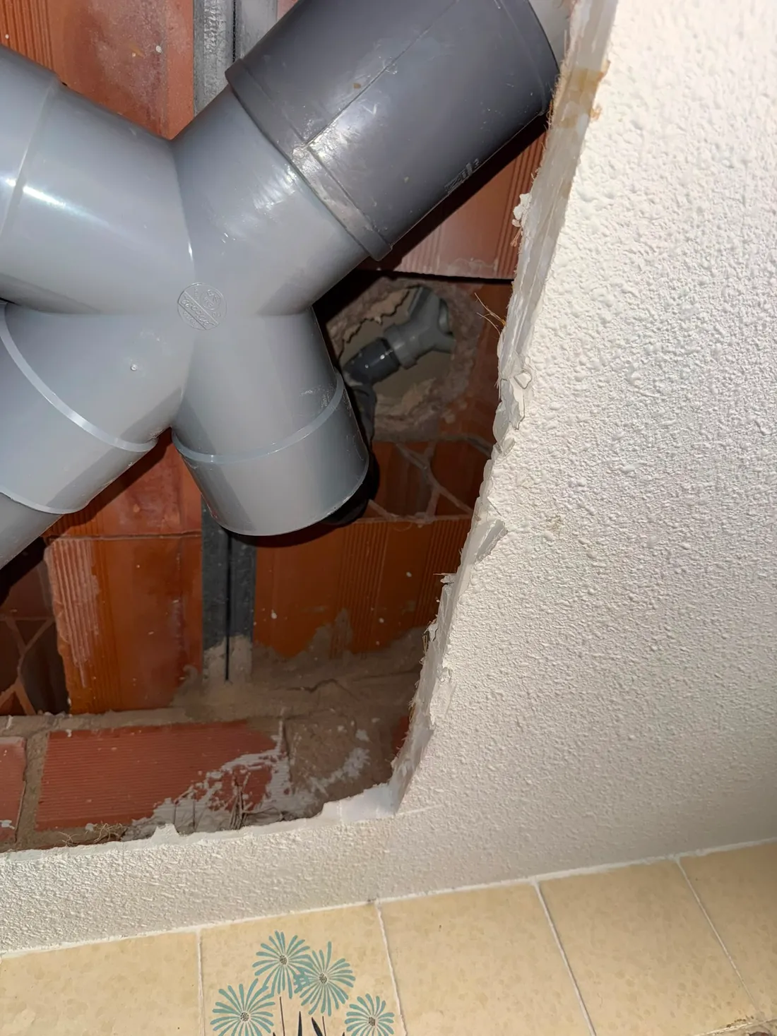Derivación en Y de tuberías de PVC resuelta dentro del techo abierto de un baño