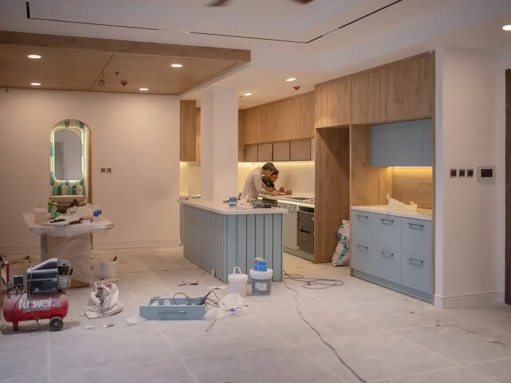 Interior de una vivienda en obra de reforma con técnicos trabajando: iluminación empotrada ya instalada, mecanismos y cuadro de control en la pared, cableado por el suelo protegido y herramienta de obra