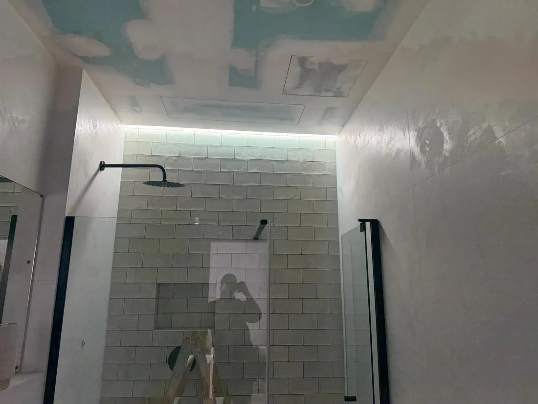 Luz indirecta empotrada en el falso techo bañando el alicatado de la ducha