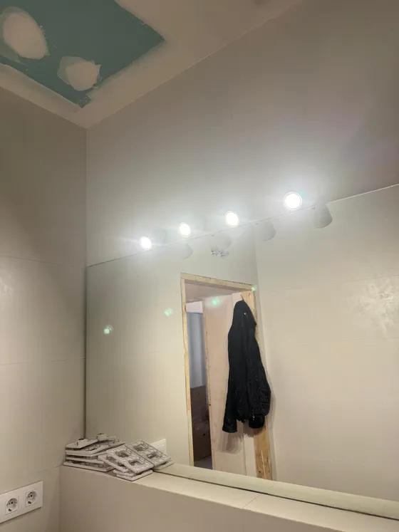 Vista del baño con la regleta de focos LED encendida sobre el espejo que ocupa todo el frente del lavabo