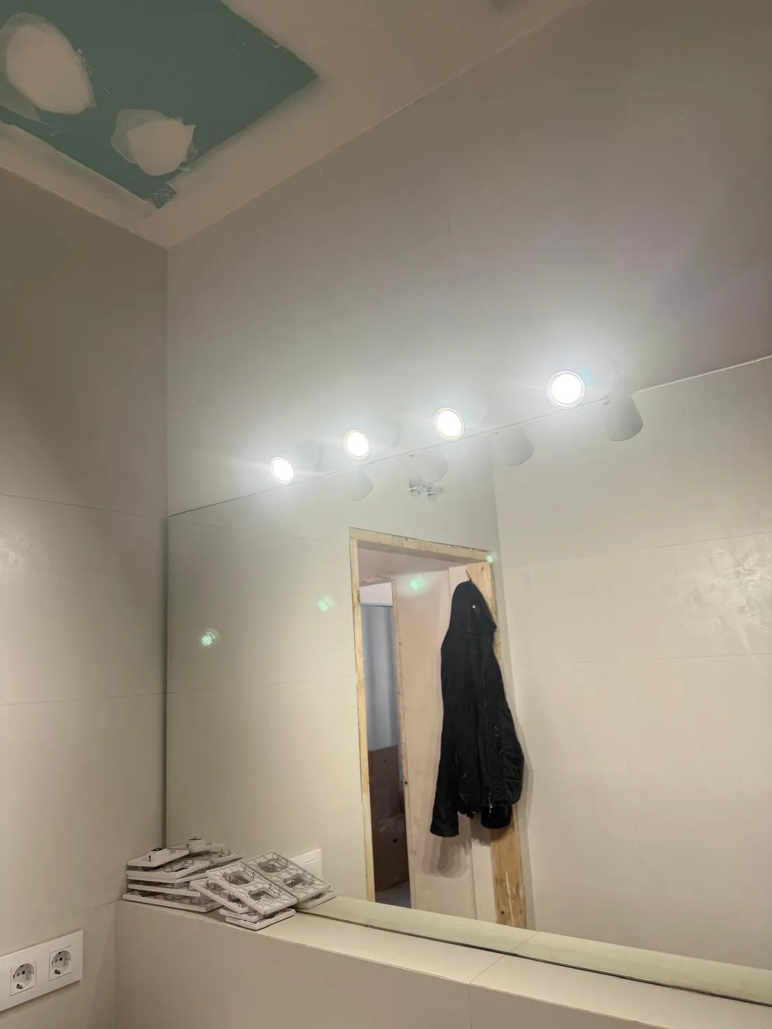 Vista del baño con la regleta de focos LED encendida sobre el espejo que ocupa todo el frente del lavabo