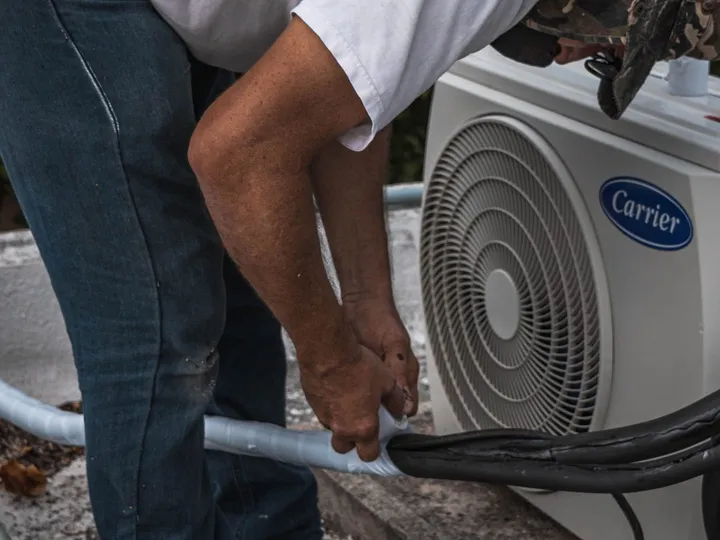 Técnico encintando y aislando la línea frigorífica junto a la unidad exterior de un equipo de aire acondicionado split