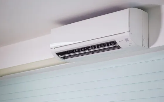 Unidad interior de un aire acondicionado split instalada en lo alto de la pared de una vivienda, con las lamas abiertas